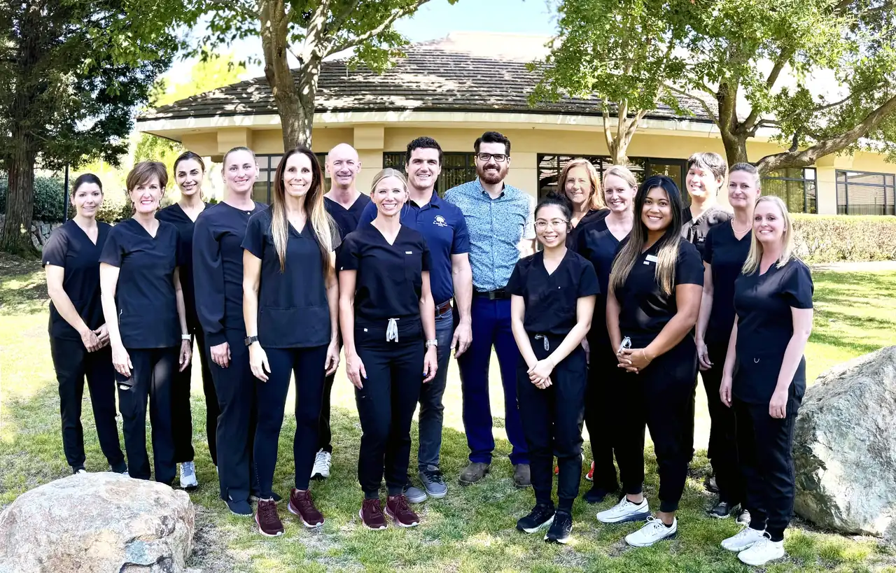 The El Dorado Hills Dental team, sixteen people including Dr. Austin and Dr. Ben Cope, standing together on a lawn in front of an office building.